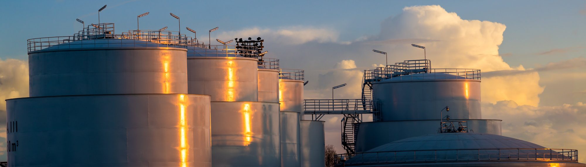 Industrielle lagertanke ved solnedgang